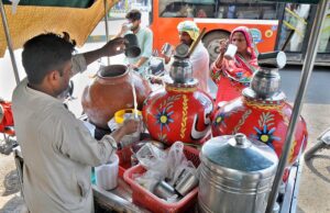 A hawker preparing and selling traditional summer drink lassi to customers, offering refreshment during the extreme hot weather in the city