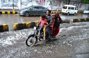 A family on the way on motorcyclist during rain in the city.