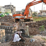 Labourers busy in construction work at Park Road with the help of heavy machinery during development work in the Federal Capital