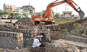 Labourers busy in construction work at Park Road with the help of heavy machinery during development work in the Federal Capital