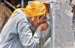 In scorching heat, a person quenches his thirst with water from a cooler in the city.