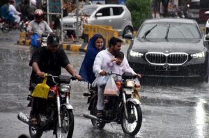 Vehicles passing through rain water accumulated on road in Kalma Chowk during heavy rain in the city.