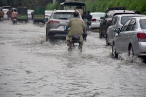 Vehicles passing through rain water accumulated on road in Kalma Chowk during heavy rain in the city.