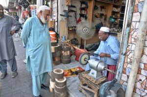 A blacksmith is sharpening knives and axes at his workplace to sell them to the butchers for using them to slaughter sacrificial animals during Eid-ul-Azha