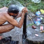 A porter bathing under water pump at Railway Station during scorching hot day in Provincial Capital