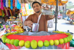 A vendor preparing and displaying a traditional summer drink Shikanjabeen to attract customers at Ghanta Ghar Chowk.