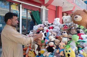 vendor displaying baby dolls to attract customers at his road side setup.