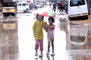 Little Girls having fun under umbrella during the rain in Provincial Capital.