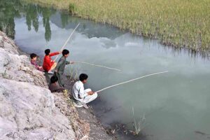 Youngster fishing in traditional way on the bank of canal.
