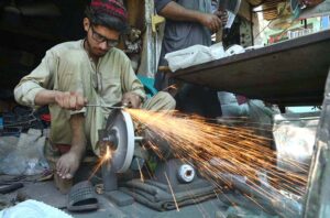 Blacksmith busy in sharpening knives to be used for slaughtering sacrificial animals ahead of Eid-ul Azha at Hashtnagri area.