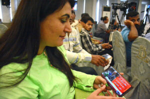 A lady watching live fiscal 2024-25 budget speech of Federal Minister for Finance and Revenue Muhammad Aurangzeb on her mobile phone.