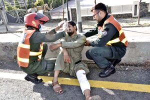Rescue 1122 officials providing first aid service to an injured person of a road accident.