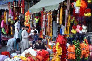 People purchasing the decorative stuff for sacrificial animals as shopkeepers displaying the decorative stuff for sacrificial animals to attract the customers at his shop in connection with upcoming Eid-ul-Azha