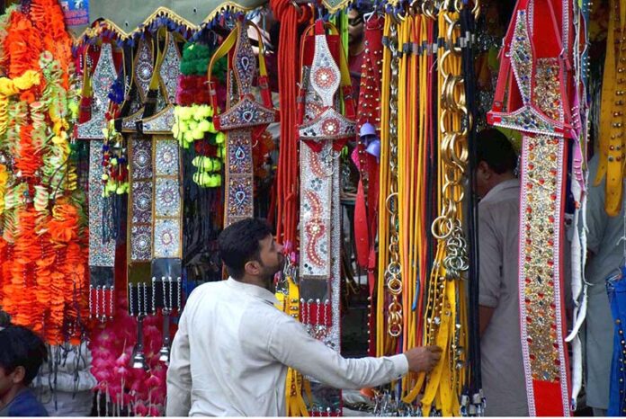 People purchasing the decorative stuff for sacrificial animals as shopkeepers displaying the decorative stuff for sacrificial animals to attract the customers at his shop in connection with upcoming Eid-ul-Azha