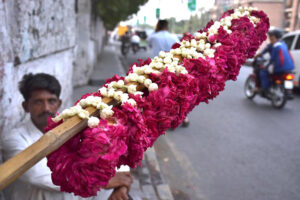 A vendor waiting for customers, selling flower garlands on the roadside.