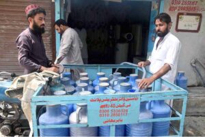 Water supplier fills clean water cans for sale to local shopkeepers, ensuring access to safe drinking water for the community in twin cities