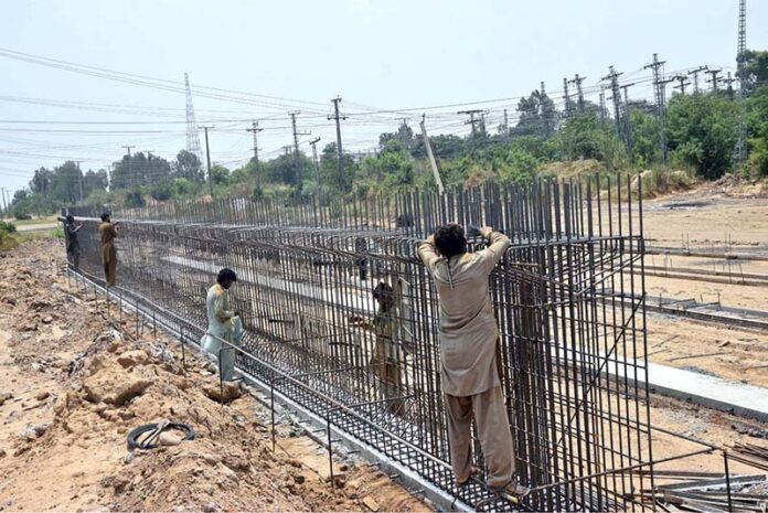 Labourers busy in construction work of flyover at under construction 10th Avenue during development work in Federal Capital