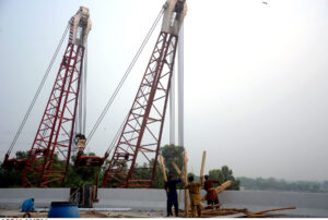 Labourers busy in construction work with the help of heavy machinery during development work in the Ravi River Road.