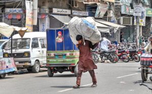 A young trash collector on the way carrying a bag filled with recycling items at Circular Road in the city .