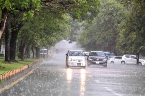 People standing under the bus stop shed at Expressway to take shelter during rain that experienced the Federal Capital.
