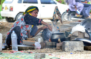 A gypsy woman busy in cooking food for her family under the shadow of flyover at Qasimabad.