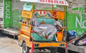 A three-wheeler rickshaw driver taking a nap on his Changi during a hot weather in the city