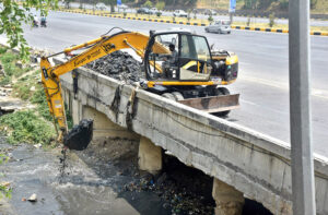 CDA staff busy cleaning the nullah with heavy machinery at Srinagar Highway in preparation for the monsoon season in the Federal Capital.