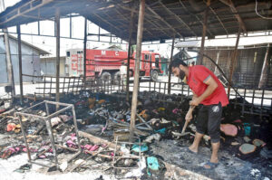 A stall holder examine the burnt remains of his stall which burnt due to yesterday’s fire at the H-9 Weekly Bazaar