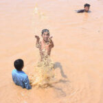 Children enjoying bath in the rain water accumulated in water pond in the Federal Capital
