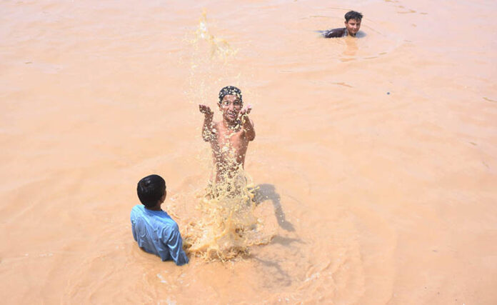 Children enjoying bath in the rain water accumulated in water pond in the Federal Capital