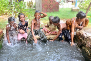 Gypsy children enjoying bathing to get relief from hot and humid weather in the city.