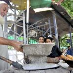An elderly vendor roasting corn cob for customers at his roadside setup in Federal Capital