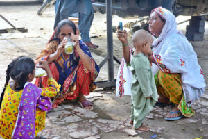 A woman with her children drinking sugarcane juice during hot weather in the city.