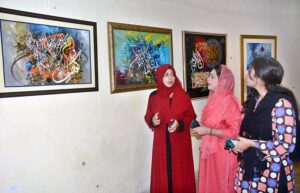 Art lovers keenly view a Quranic calligraphy painting,appreciating the intricate details and spiritual significance at the Arts Council exhibition.