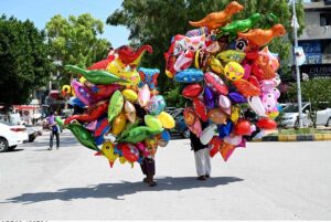 Vendors selling colorful balloons to attract customers while shuttling on road at G-9 Markaz in the Federal Capital