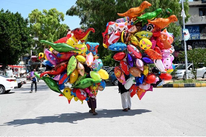 Vendors selling colorful balloons to attract customers while shuttling on road at G-9 Markaz in the Federal Capital
