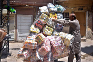 A delivery man secures a snacks bag with a knot, ready to be carried on his motorbike to supply in the market in Twin cities.
