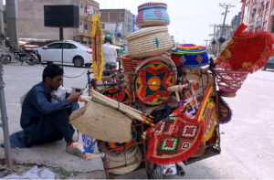 A street vendor browses his mobile beside his handcrafted wares displayed on his bicycle, waiting for customers in Ghouri Town,Federal Capital.
