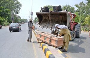 Parks and Horticulture Authority staff are installing plant pots on the road divider in front of the DC office.