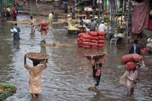 A labourer sitting on the potatoes and Onion sacks after unloading from the delivery truck as the rain water accumulated at fruit and vegetable market after heavy rain that experienced in the Provincial Capital.