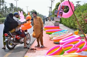 A vendor displaying air filled plastic bath tubs for children to attract the customers at his roadside setup.