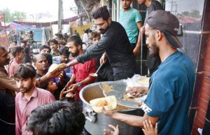 People are standing in a queue to receive free food being distributed by volunteers during Holy month of Muharram ul Harram.