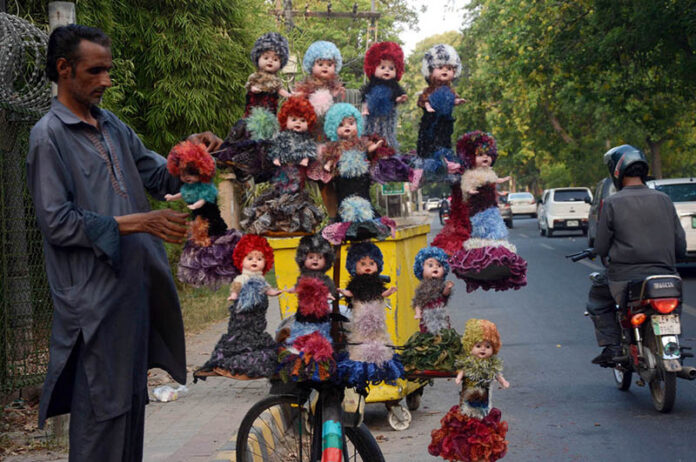 A vendor displaying dolls on his bicycle to attract customers at Roadside