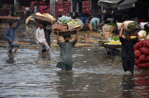A labourer sitting on the potatoes and Onion sacks after unloading from the delivery truck as the rain water accumulated at fruit and vegetable market after heavy rain that experienced in the Provincial Capital.