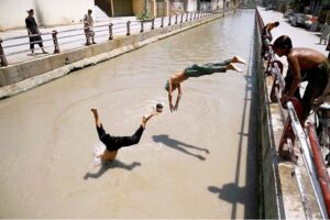 Youngster diving into the canal to get some relief from extreme hot weather in the city