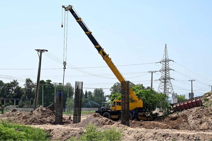 Labourers busy in construction work of flyover at under construction 10th Avenue during development work in Federal Capital