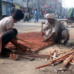 Carpenters preparing bamboo ladder outside their shop in a local market