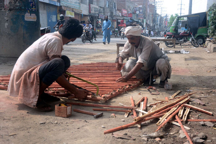Carpenters preparing bamboo ladder outside their shop in a local market