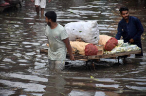 A labourer sitting on the potatoes and Onion sacks after unloading from the delivery truck as the rain water accumulated at fruit and vegetable market after heavy rain that experienced in the Provincial Capital.