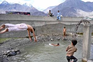 Youngsters jumping and bathing in water pound to get relief from hot weather in city.
